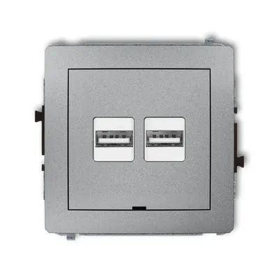 Ładowarka podwójna USB typu A+A Karlik DECO w kolorze srebrny metalik, z dwoma portami USB do ładowania urządzeń.