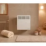 Grzejnik elektryczny Thermoval T18 Next 500W WiFi zamontowany na ścianie w łazience, obok ręcznik i dywanik.