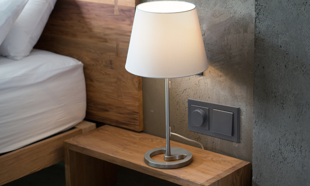 Ściemniacz i włącznik Ospel w kolorze szary grafit z serii Sonata. Zamontowany na betonowej powierzchni w sypialni.