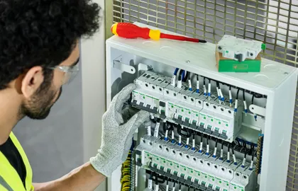 Elektryk montuje aparaturę modułową w otwartej rozdzielnicy elektrycznej